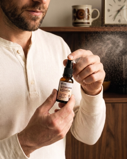 Man using 5 mushroom complex spray, functional mushroom supplement in amber bottle with mist spray