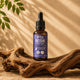 Flacon en verre ambré 30 ml de gouttes de Reishi Pure Croft avec pipette compte-gouttes noire, mis en scène sur du bois flotté naturel.